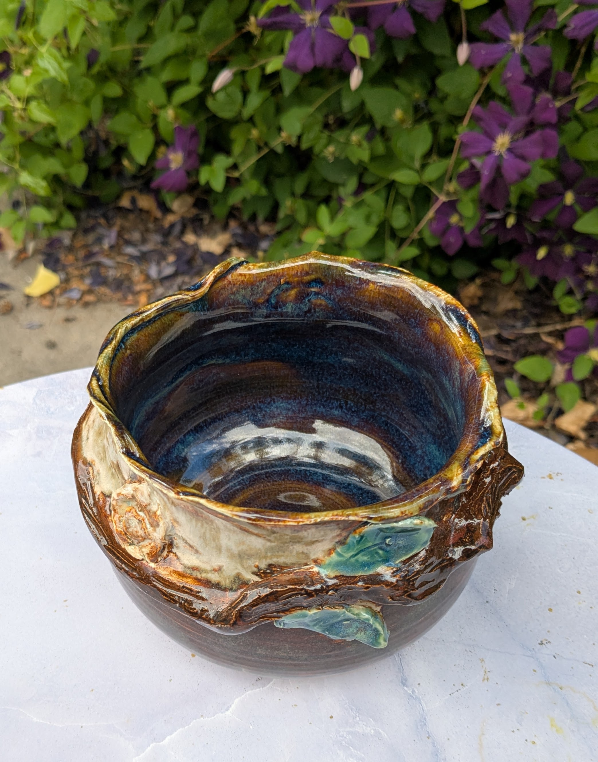 Small Decorative Bowl / Vase - One thing I've learned through art, throughout my life, is how to make an "accident" a little more beautiful through intention. 

Sometimes, when a pot flops on the wheel, you have to let it go, and re-use the clay for something else. Other times, you can curl the edges down to give them a sculptural shape, and add a branch and leaves to make the whole piece look more organic and inspired by nature. 

I was pretty happy with the results of my choice this time around - the interior has an almost watery-blue color to accent the earthen look of the exterior. You could use it as a decorative piece, display small flowers in it, serve small side dishes from it, or stash your keys and wallet in this lovely little vessel. - 40